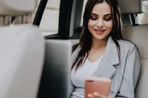 Femme dans une voiture utilisant un téléphone et ordinateur.